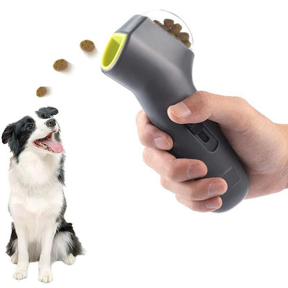 A hand holding the Everyday Essentials™ Pet Treat Launcher, dispensing treats towards a happy dog.